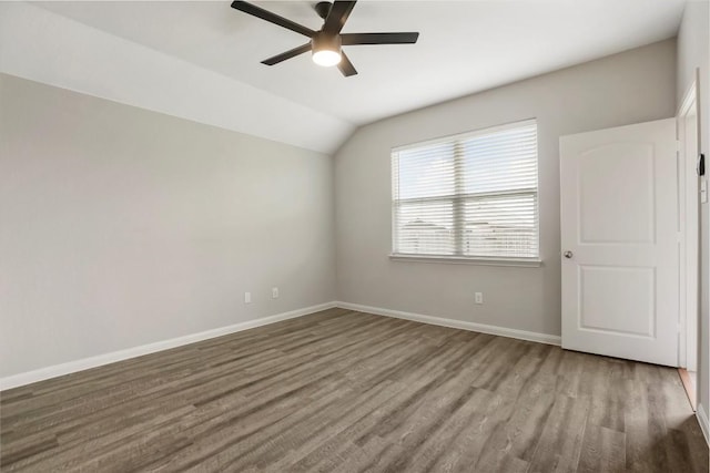 unfurnished room with a ceiling fan, vaulted ceiling, wood finished floors, and baseboards