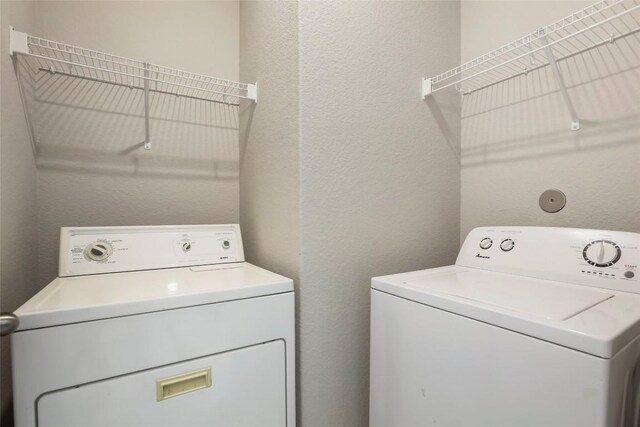 laundry room featuring a textured wall, washing machine and clothes dryer, and laundry area