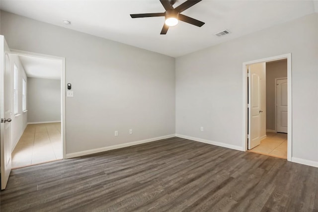 spare room featuring wood finished floors, visible vents, a ceiling fan, and baseboards