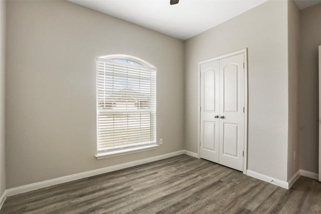 unfurnished bedroom with a closet, ceiling fan, wood finished floors, and baseboards