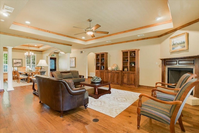 living room with crown molding, arched walkways, visible vents, and a raised ceiling