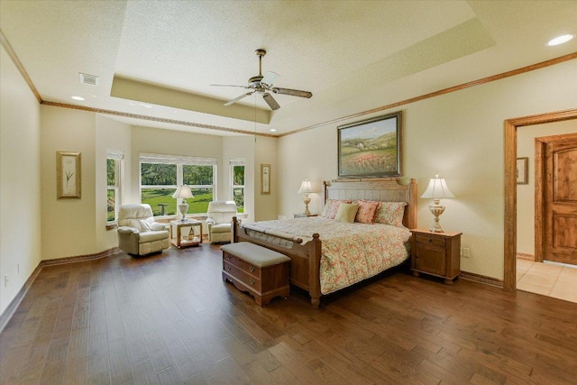bedroom with recessed lighting, hardwood / wood-style floors, baseboards, visible vents, and a tray ceiling