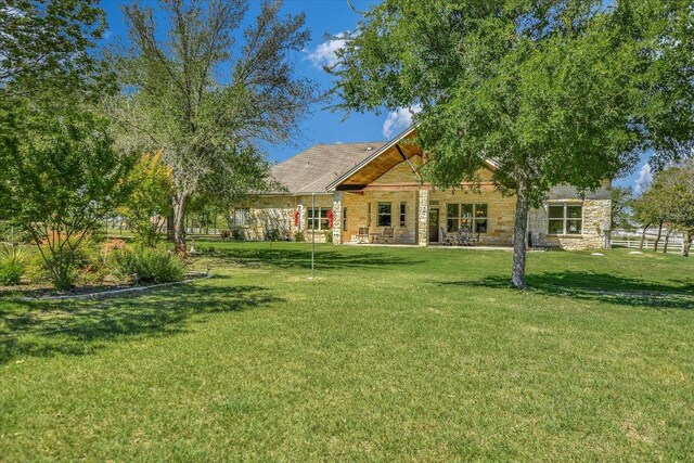 rear view of property with a lawn and stone siding