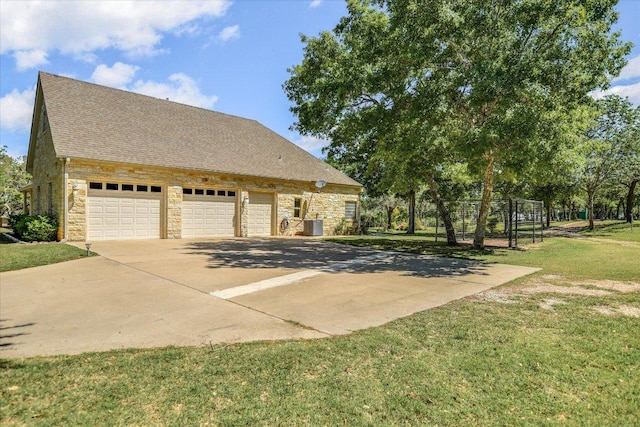 view of side of property featuring a shingled roof, a garage, a lawn, stone siding, and concrete driveway