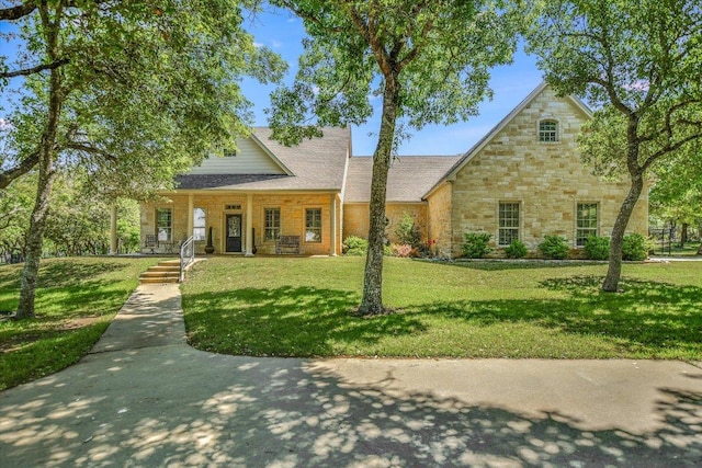 view of front facade featuring covered porch, a front lawn, and stone siding