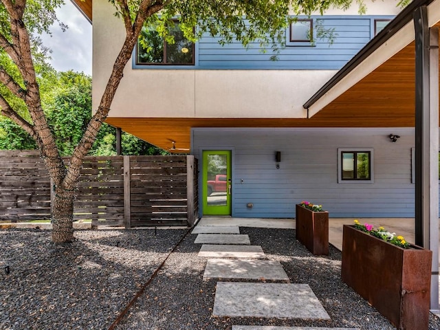 entrance to property featuring fence and stucco siding