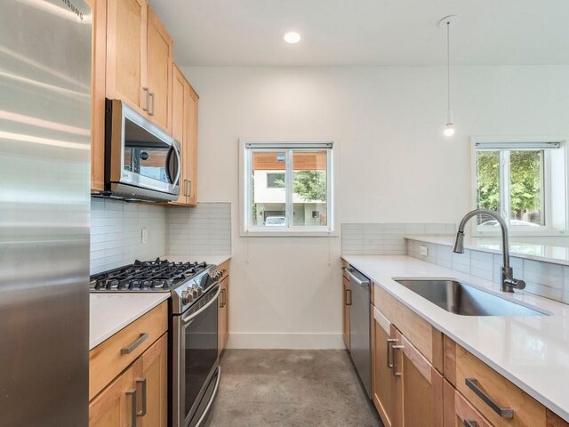 kitchen with tasteful backsplash, stainless steel appliances, light countertops, a sink, and baseboards