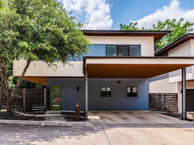 contemporary home featuring driveway, a carport, and fence