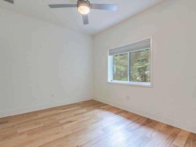empty room with a ceiling fan, visible vents, wood finished floors, and baseboards