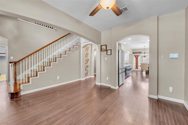3306 Castleton Dr, Killeen, TX 76542 - unfurnished living room featuring visible vents, stairs, arched walkways, dark wood finished floors, and ceiling fan with notable chandelier