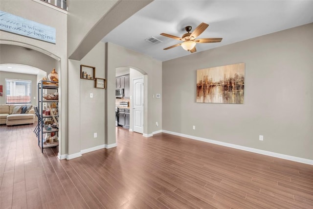 3306 Castleton Dr, Killeen, TX 76542 - unfurnished living room with visible vents, arched walkways, ceiling fan, and wood finished floors