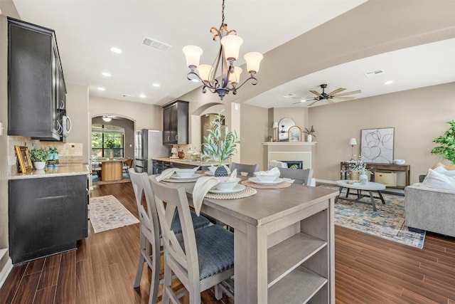 3306 Castleton Dr, Killeen, TX 76542 - dining room featuring ceiling fan, arched walkways, a fireplace, dark wood-style floors, and a chandelier