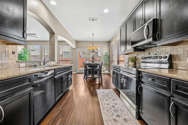 3306 Castleton Dr, Killeen, TX 76542 - kitchen featuring stainless steel appliances, a chandelier, dark wood-type flooring, dark cabinets, and decorative backsplash