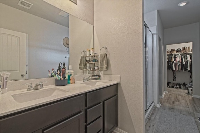 full bathroom with visible vents, a shower stall, double vanity, and a sink