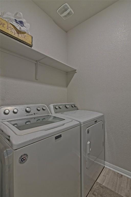 clothes washing area featuring visible vents, separate washer and dryer, laundry area, and baseboards