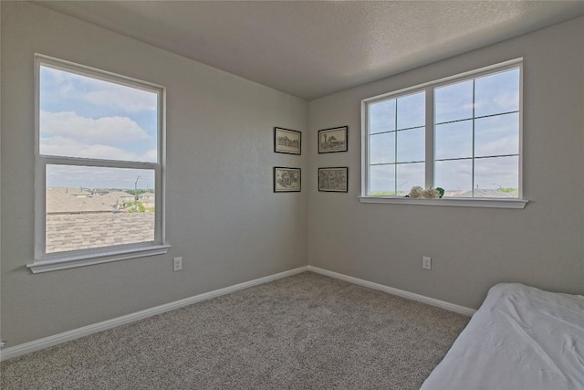 unfurnished bedroom featuring a textured ceiling, baseboards, and carpet floors