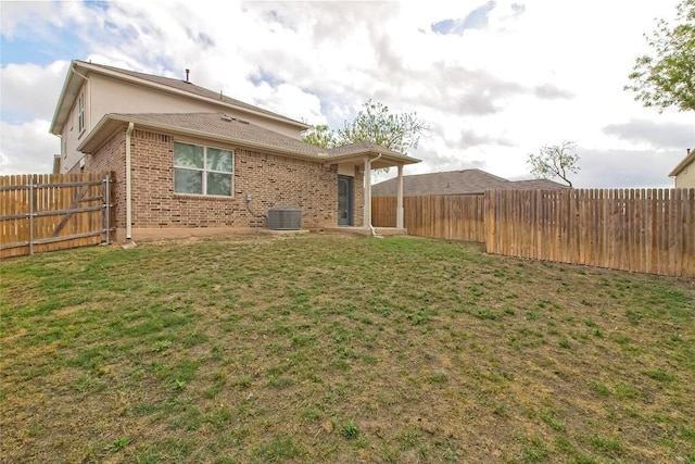 back of property featuring brick siding, a fenced backyard, a yard, and central air condition unit