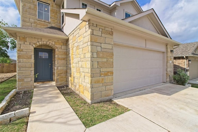 entrance to property with stucco siding, driveway, and stone siding
