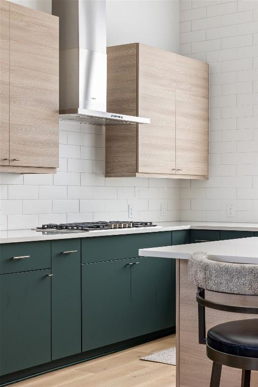 kitchen with green cabinets, light countertops, and wall chimney exhaust hood