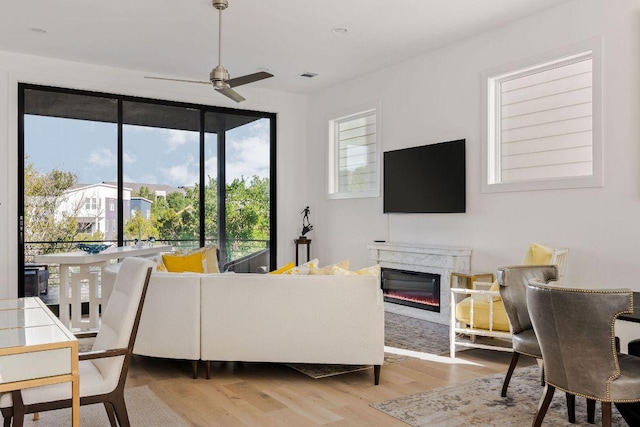 living room featuring visible vents, wood finished floors, a healthy amount of sunlight, and a premium fireplace