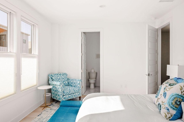 bedroom with visible vents, connected bathroom, and baseboards