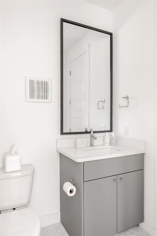 half bathroom featuring visible vents, toilet, vanity, and baseboards