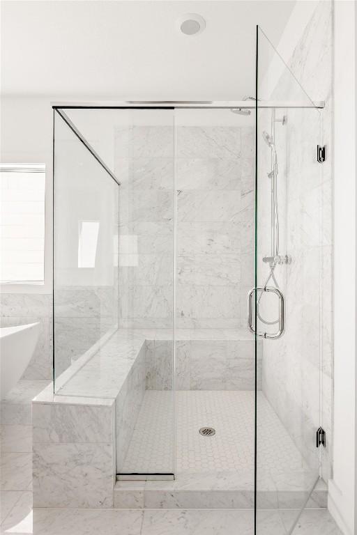 bathroom featuring a freestanding tub and a marble finish shower