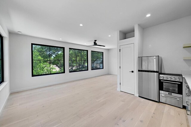 2001 Circle Hvn, Austin, TX 78741 - unfurnished living room with light wood finished floors, plenty of natural light, a ceiling fan, and recessed lighting
