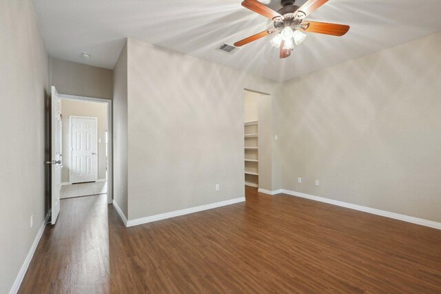 spare room with baseboards, visible vents, a ceiling fan, and dark wood-type flooring