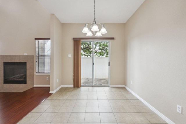 doorway with a tiled fireplace, a notable chandelier, and baseboards