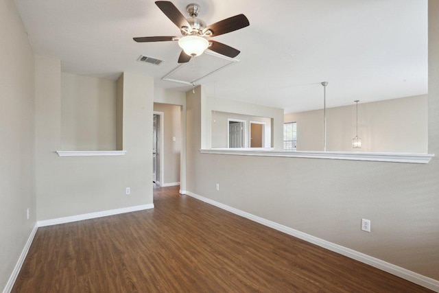unfurnished living room featuring attic access, ceiling fan, wood finished floors, and baseboards