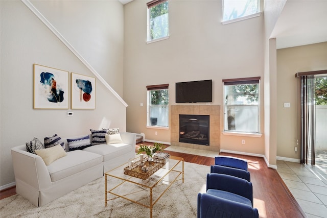 living room featuring a towering ceiling, wood finished floors, and a healthy amount of sunlight