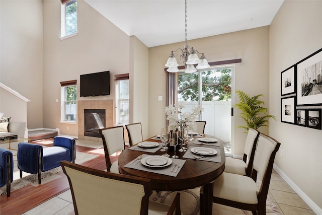 dining room with light tile patterned floors, a wealth of natural light, a high ceiling, and a notable chandelier