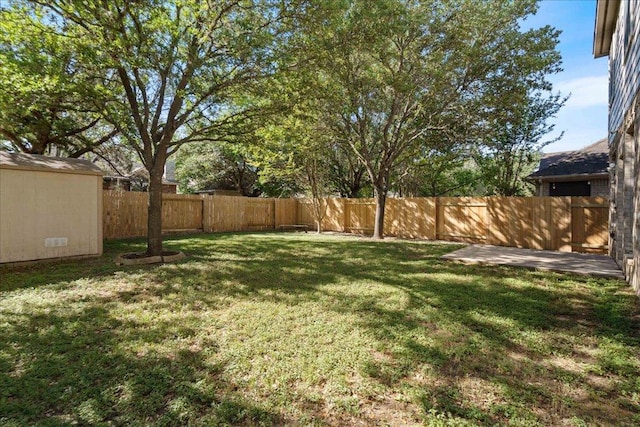 view of yard with a storage shed, an outbuilding, and a fenced backyard