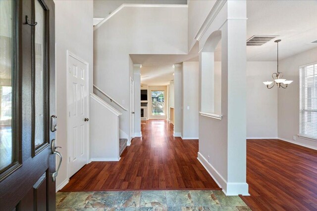 entrance foyer featuring an inviting chandelier, a wealth of natural light, visible vents, and wood finished floors