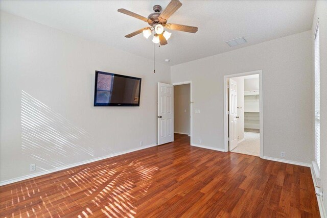 interior space featuring visible vents, ceiling fan, baseboards, wood finished floors, and a walk in closet