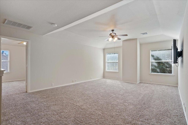 carpeted empty room featuring lofted ceiling, visible vents, a ceiling fan, and baseboards