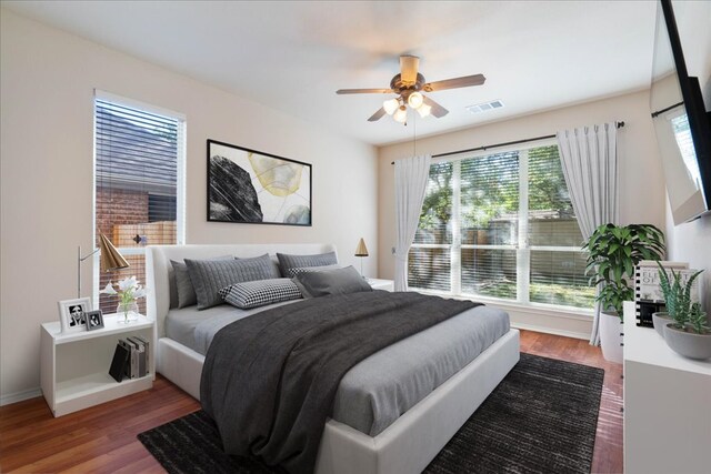 bedroom featuring baseboards, visible vents, wood finished floors, and ceiling fan