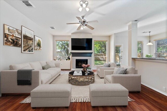 living area featuring visible vents, wood finished floors, ceiling fan, and a fireplace