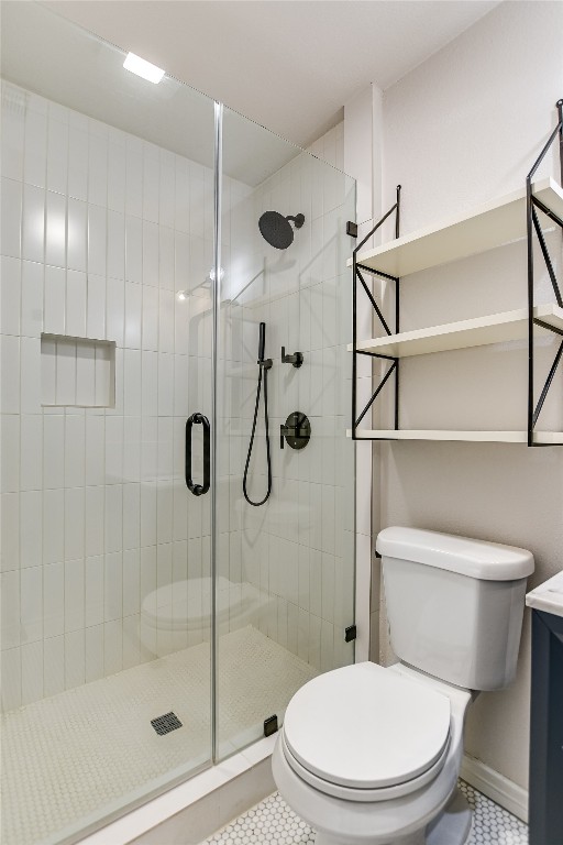bathroom featuring tile patterned floors, toilet, and a shower stall