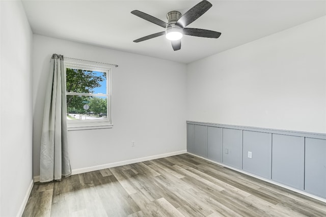 empty room with baseboards, wood finished floors, and ceiling fan