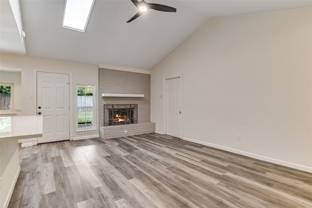 unfurnished living room featuring baseboards, a brick fireplace, wood finished floors, a ceiling fan, and high vaulted ceiling