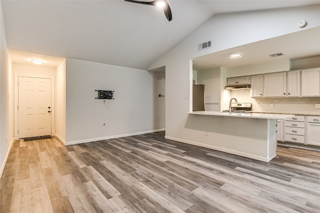 unfurnished living room featuring visible vents, ceiling fan, light wood finished floors, and vaulted ceiling