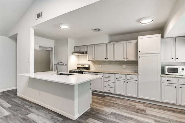 kitchen with a sink, appliances with stainless steel finishes, visible vents, light countertops, and under cabinet range hood