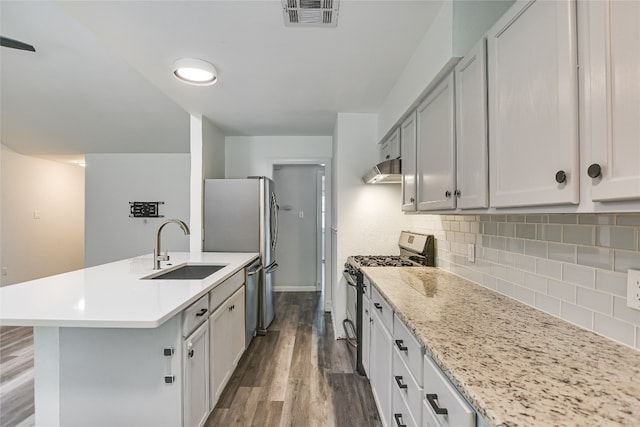 kitchen with under cabinet range hood, appliances with stainless steel finishes, a sink, visible vents, and dark wood-type flooring