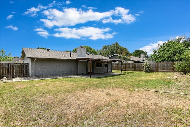 back of house with a lawn, a chimney, a fenced backyard, and a patio area