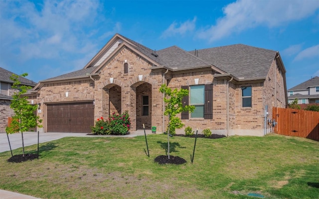 view of front of house with a front lawn, concrete driveway, an attached garage, and brick siding