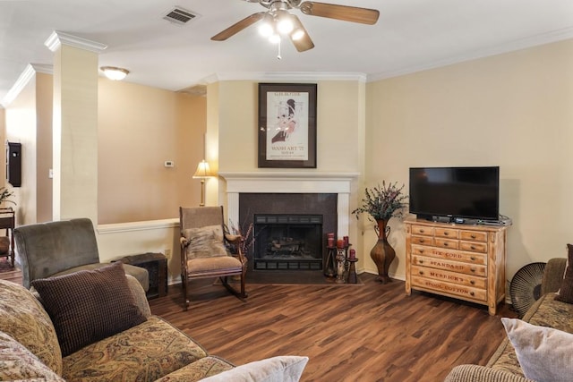 living area with a fireplace with flush hearth, visible vents, ceiling fan, ornamental molding, and wood finished floors