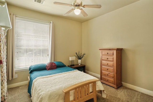 carpeted bedroom with a ceiling fan, visible vents, and baseboards