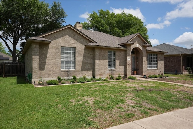 ranch-style home featuring a chimney, brick siding, fence, and a front lawn